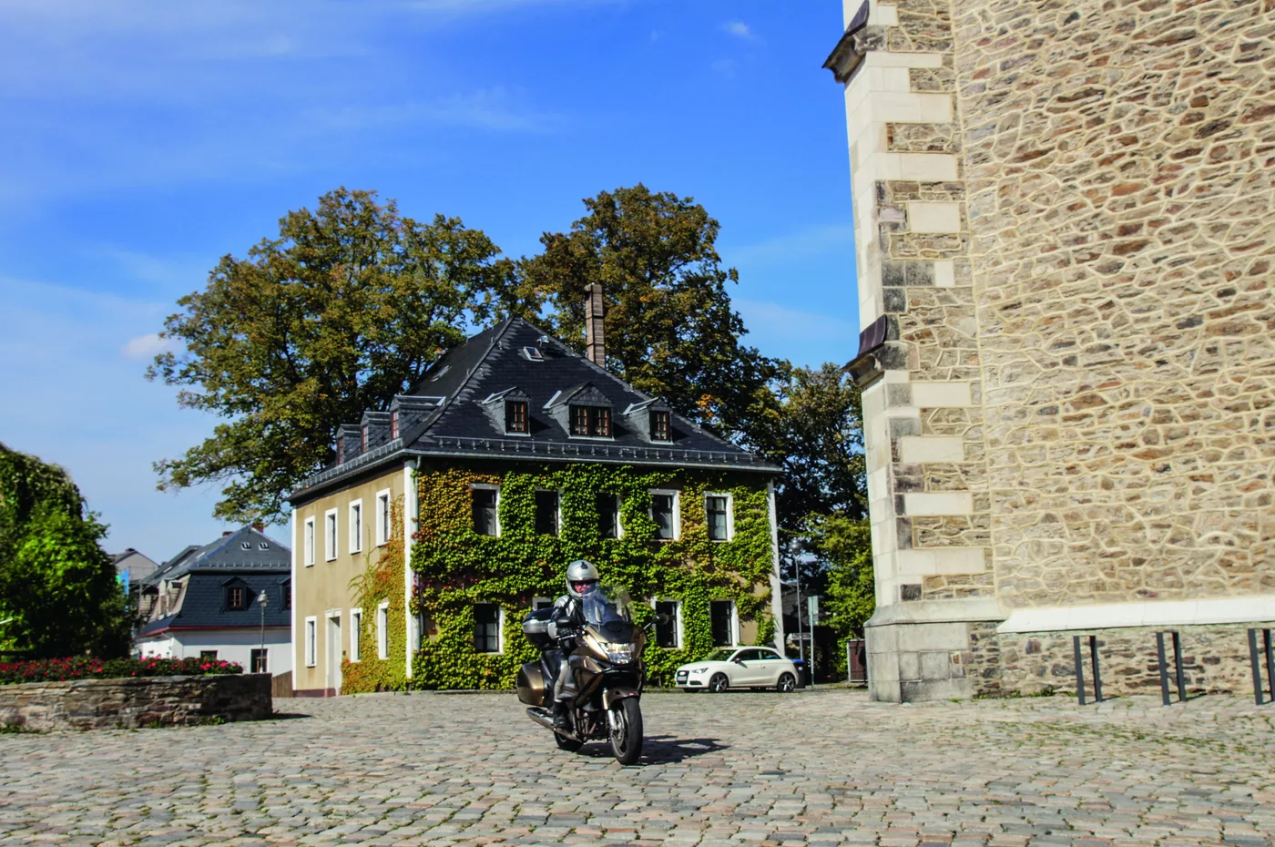 Motorrad vor Kirchturm und Bürgerhäusern in der Bergstadt Schneeberg